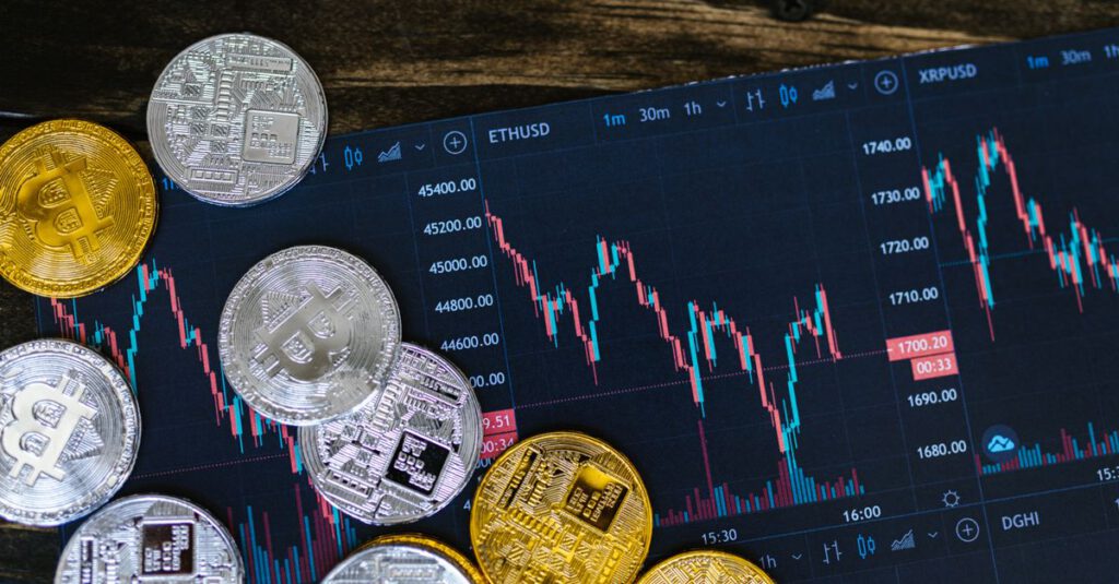 Symbolbild: Eine Bitcoin-Münze auf einem digitalen Kurschart im Hintergrund.